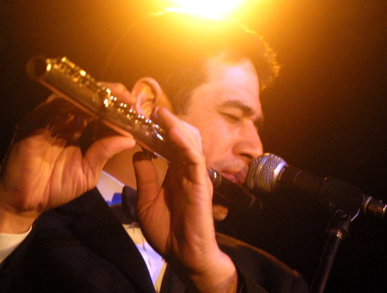 Maestro Bobby Ramirez in a tuxedo playing a flute
