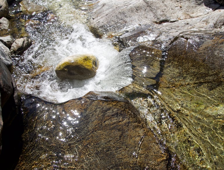 water falling on rocks. sun reflecting off water.
