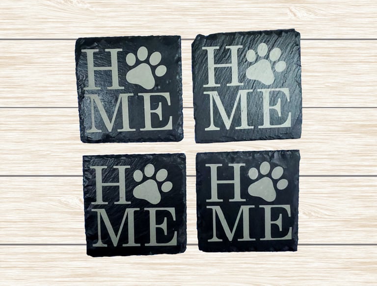 a set of four slate coasters engraved with the word home.