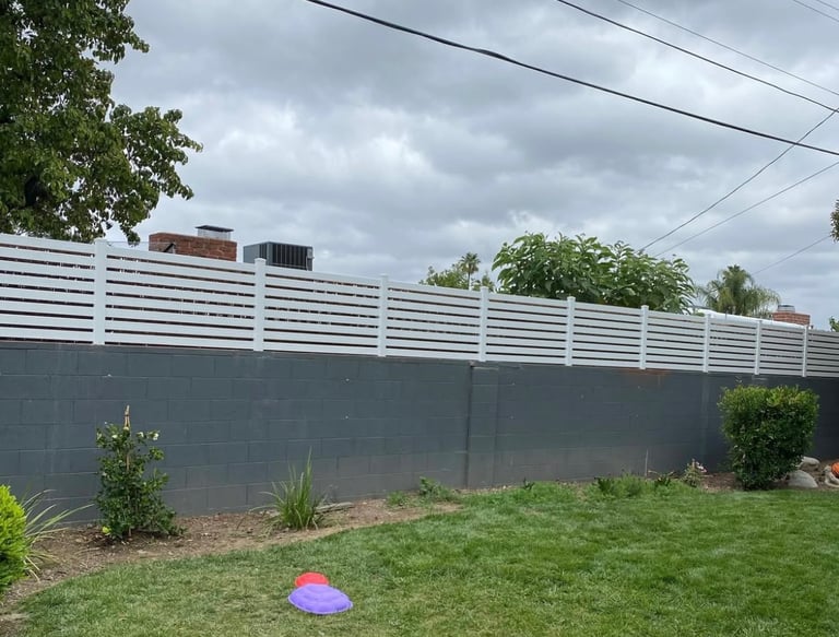Horizontal vinyl picket fencing on top of block wall.