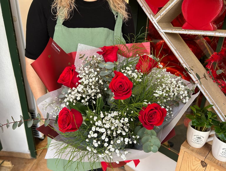 Florist holding a romantic bouquet of red roses and white baby's breath flowers.