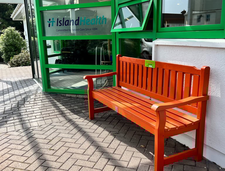 Orange bench in fron of green doors atmedical centre