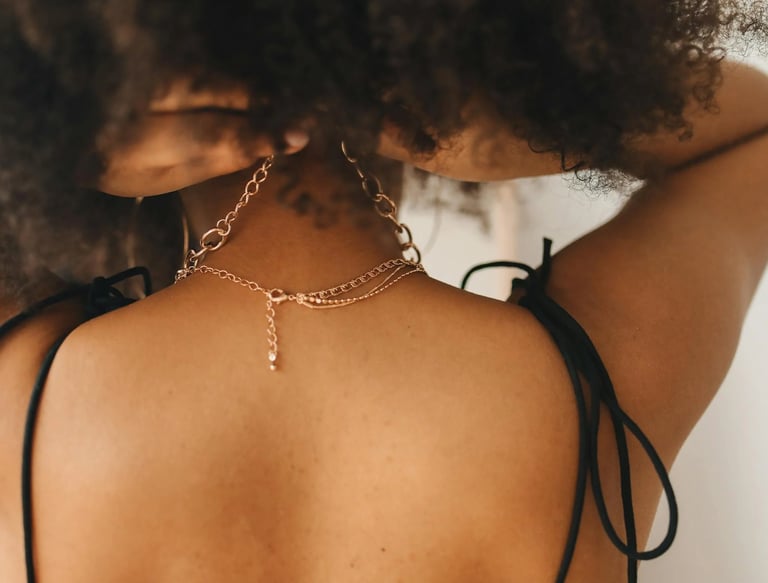 a woman with a black bralet and a gold chain link necklace
