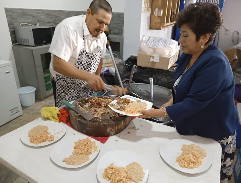 Cocinero sirviendo barbacoa en un evento, con platos de arroz y frijoles listos para los invitados.