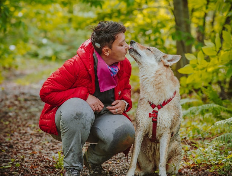 ragazza che si fa dare un bacio dal proprio cane in un bosco