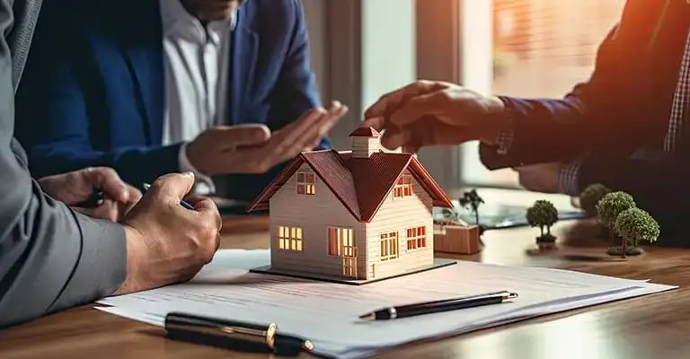 Real estate professionals discussing property maintenance and management with a miniature house mode