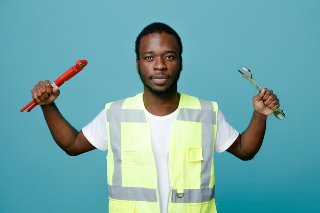 Professional plumber in a high-visibility vest holding a pipe wrench and spanner.