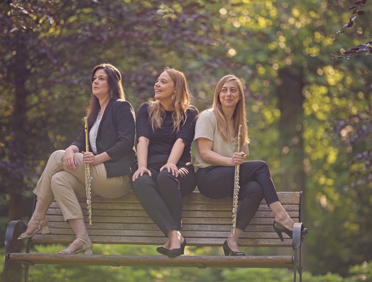 three women sitting on a bench in a park