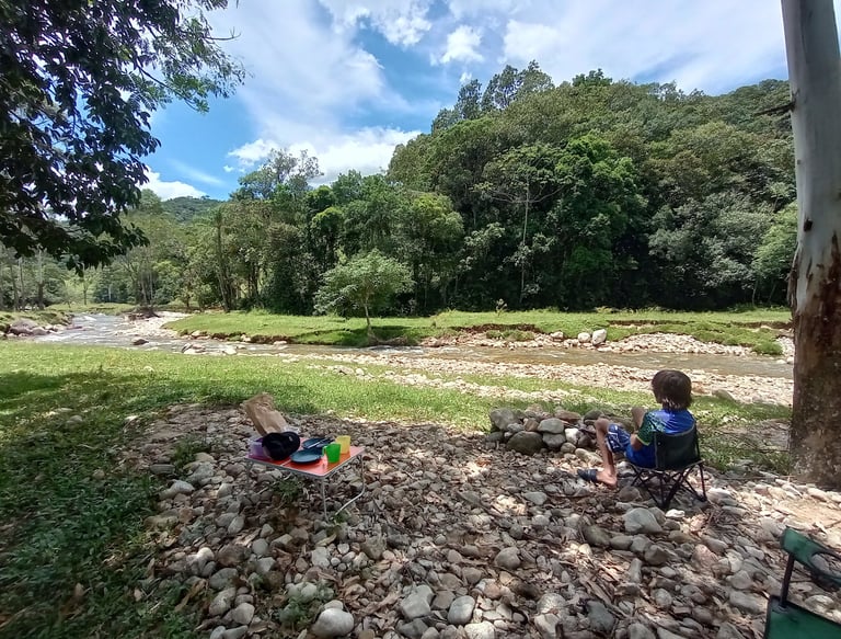 Família acampando na beira do rio em meio à natureza