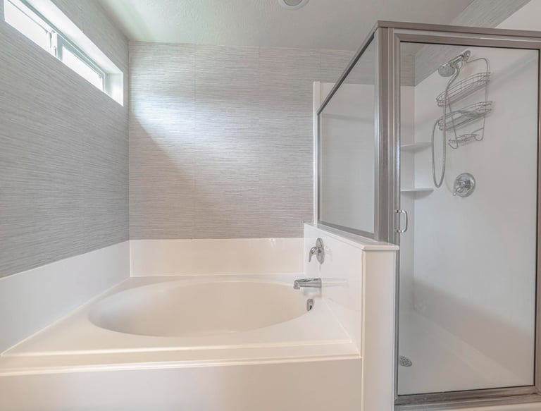 White corner bath and shower cubicle – example of a shower set‑up needing door repair in Auckland
