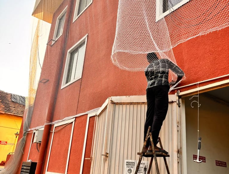 Technician from Arjilli Safety Nets fitting a pigeon net on a large warehouse window.