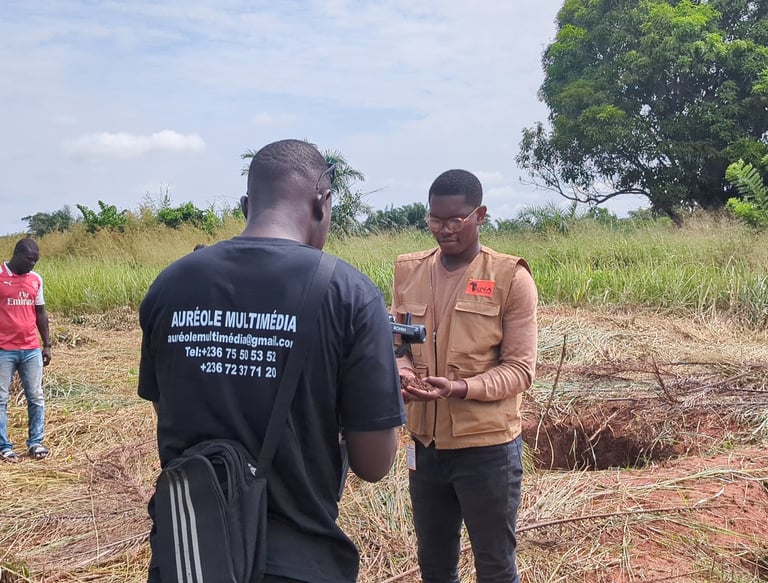 A videographer filming a man inspecting soil at a rural agricultural site for Aureole Multimedia.