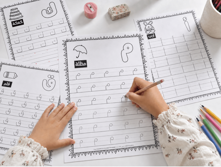 A child practicing Arabic letters on printable tracing worksheets with a pencil