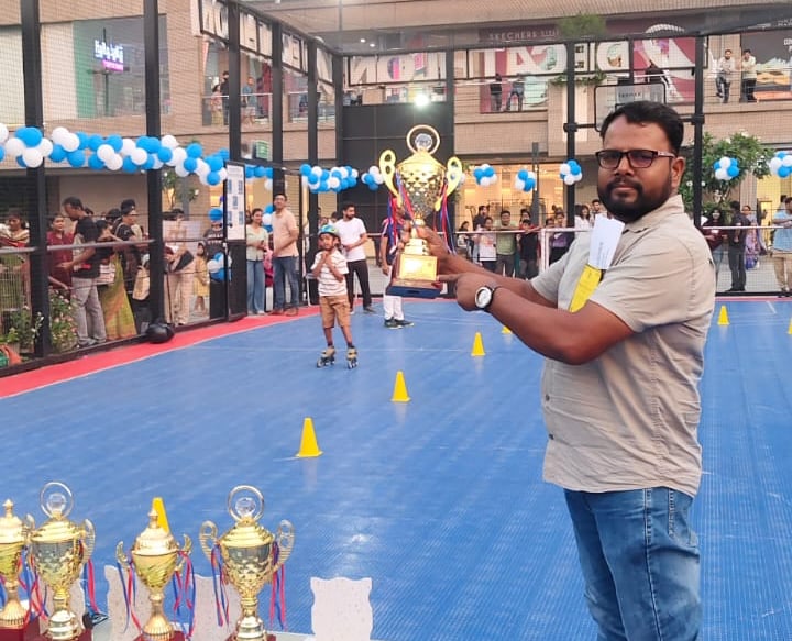 A man on roller skates holding a trophy at Nexus Select Citywalk skating event in Delhi.