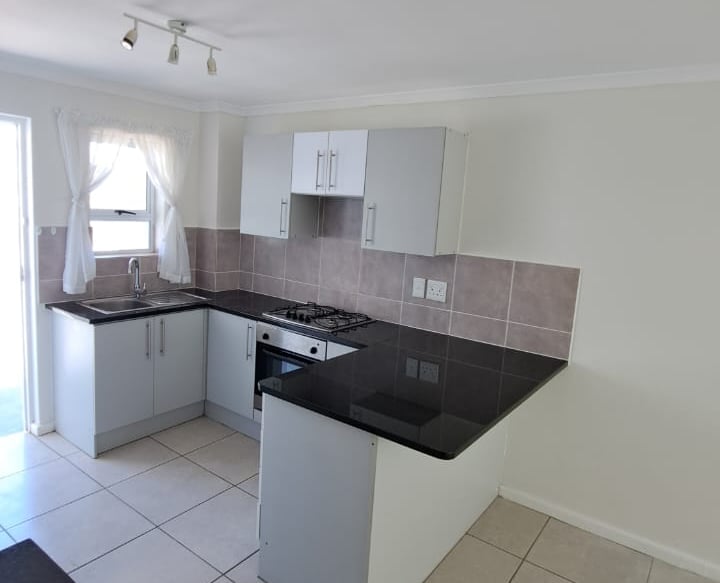 Modern small kitchen with black granite countertops, white cabinets, and gas stove stove.
