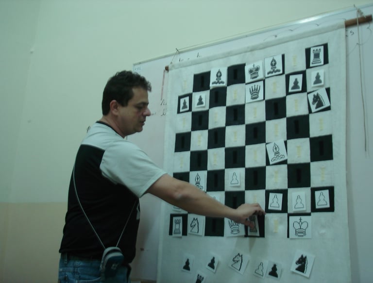 Reinaldo Mano movendo uma peça num quadro tabuleiro durante uma aula