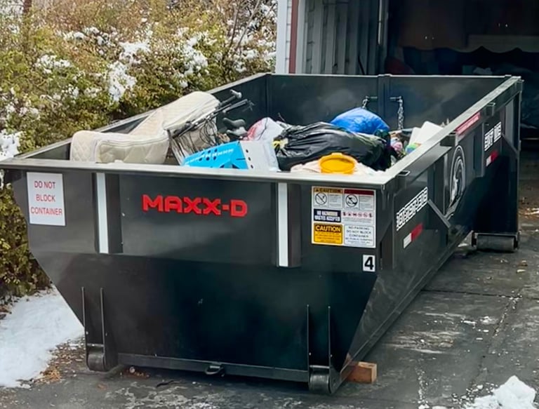 A black dumpster filled with junk