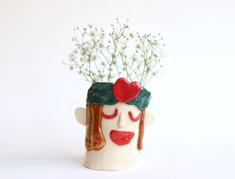 a ceramic face vase with a face on it