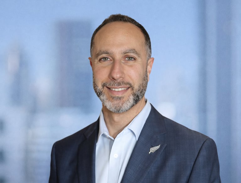 Arif Zaher headshot of a smiling businessman in a blue suit with a silver fern lapel pin.