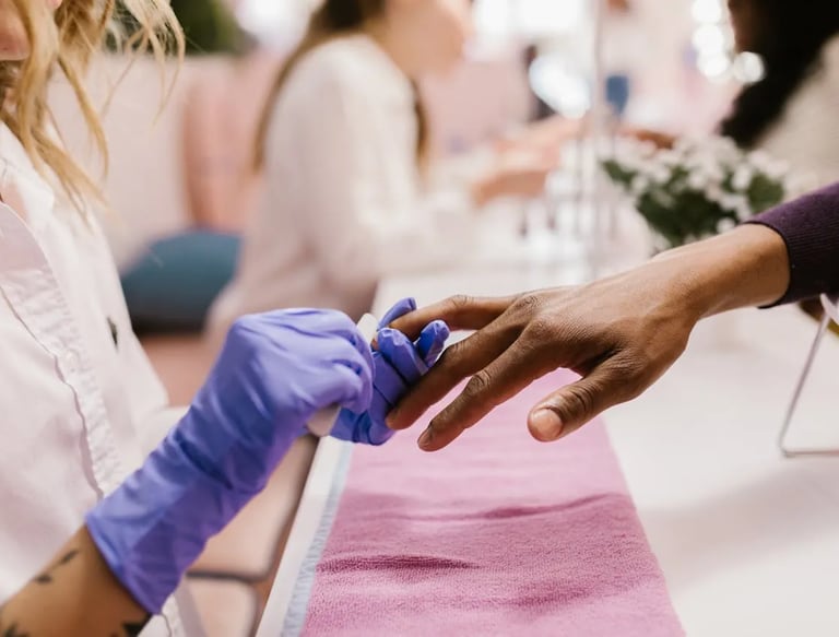 a woman is getting her nails done by a professional wearing gloves.