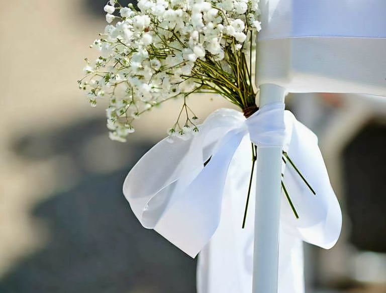 Silla para boda decorada con un liston blanco y flores