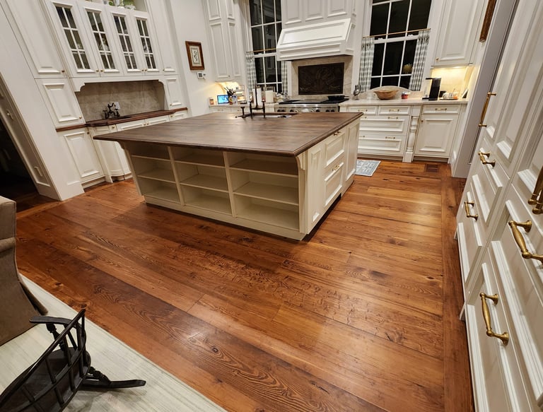 Spacious luxury kitchen featuring white cabinetry, wide-plank hardwood floors, and a large wood-top island.