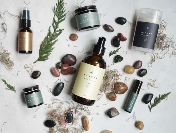 Flat lay of skincare products with herbs and stones on a white background