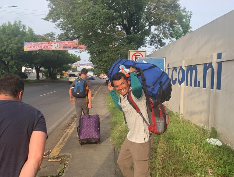 Roger smiling holding luggage over shoulders.