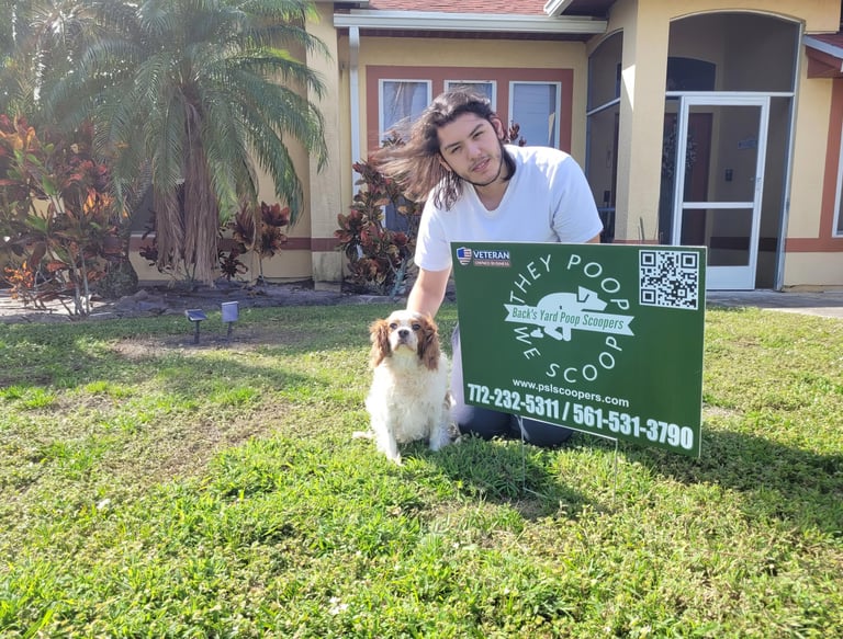 Alex smiling, one of the scoopers, posing with his dog and poop scoopers yard sign at customers home