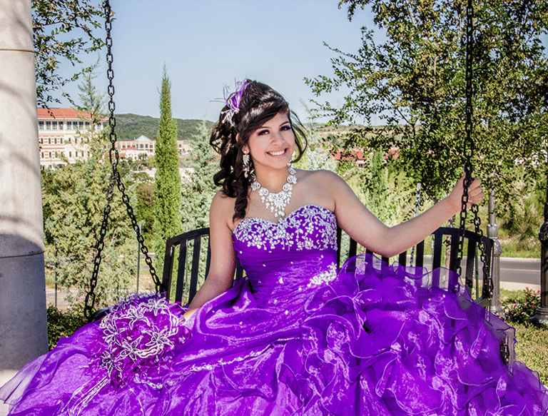 a woman in a purple quinceanera dress sitting on a bench