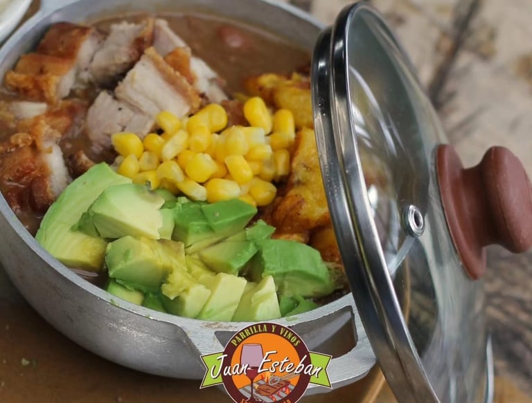 Plato típico colombiano servido en olla metálica en Parrilla y Vinos Juan Esteban, con cerdo asado,