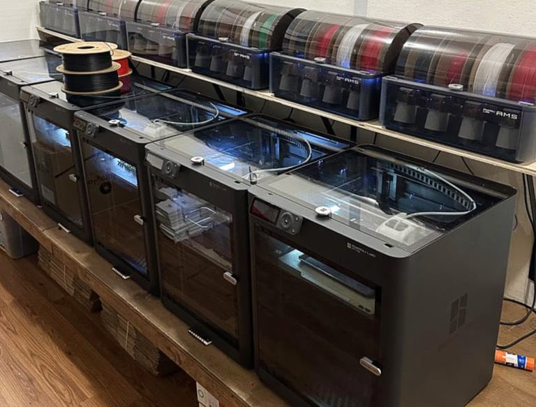 A row of Bambu Lab 3D printers with AMS filament management systems in a professional workshop.