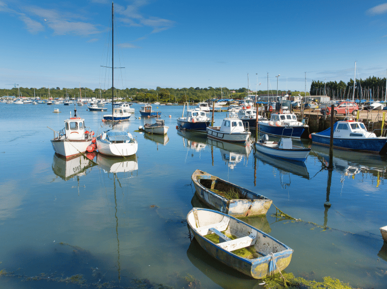 fishing boats floating in small estuary on a sunny day with blue skies