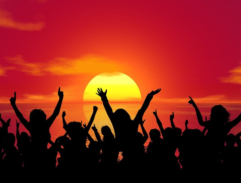 people are partying silhouetted by the setting sun in the background