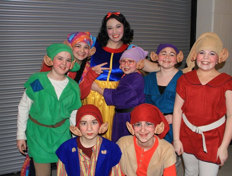 Group of people in Snow White and dwarf costumes posing indoors.