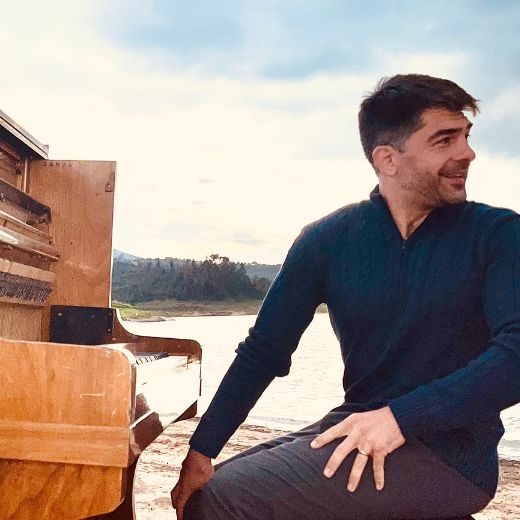 a man sitting on a bench in front of a piano