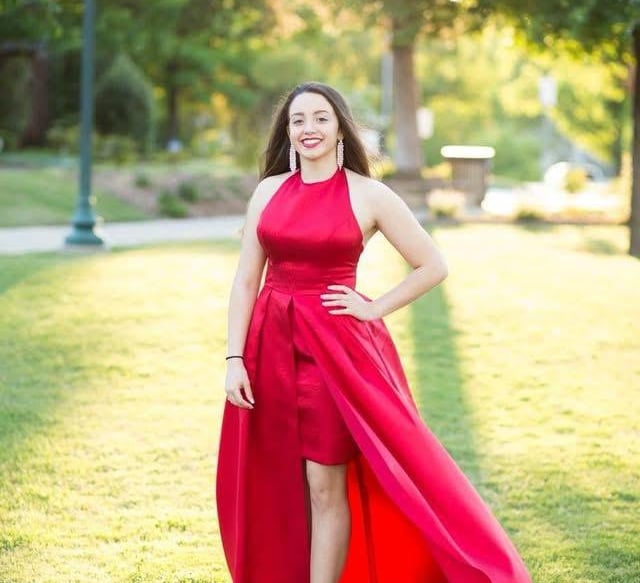 a woman in a red dress standing in the grass