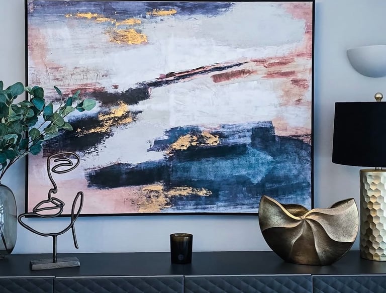 A piece of colourful modern art placed above a black counter, with gold accents in the decoration