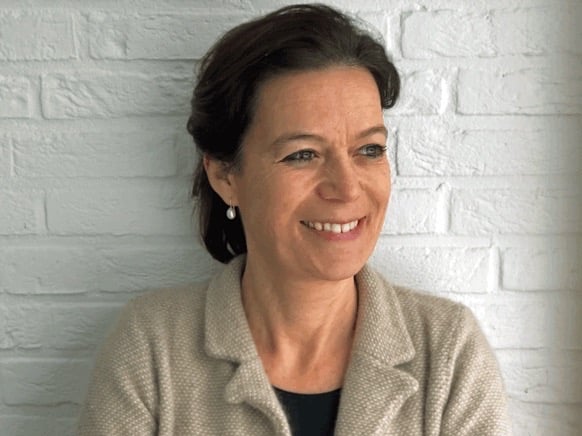 a woman in a beige jacket and earrings