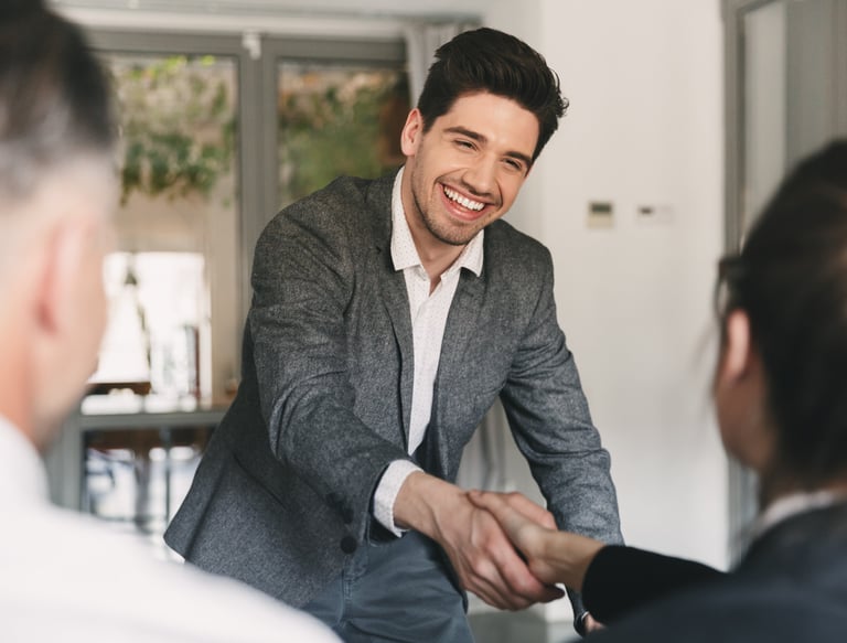 Professional person smiling and shaking hands during a meeting.