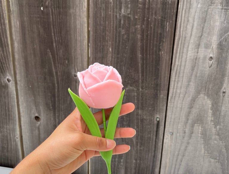 a person holding a pink flower in a vase