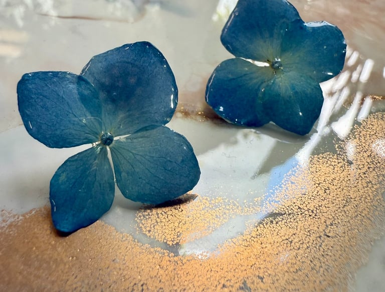two blue flowers on a plate with a gold leaf
