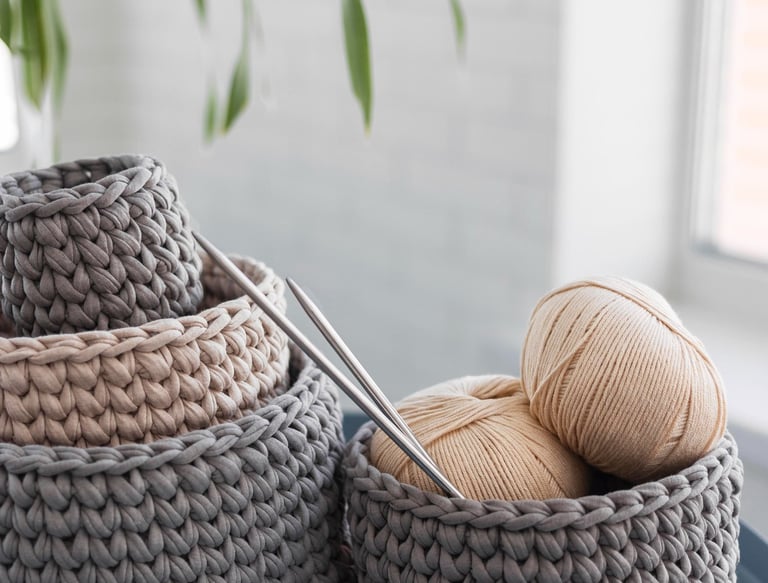 Cestas de almacenamiento hechas a mano de ganchillo en hilo gris y beige con agujas de tejer.
