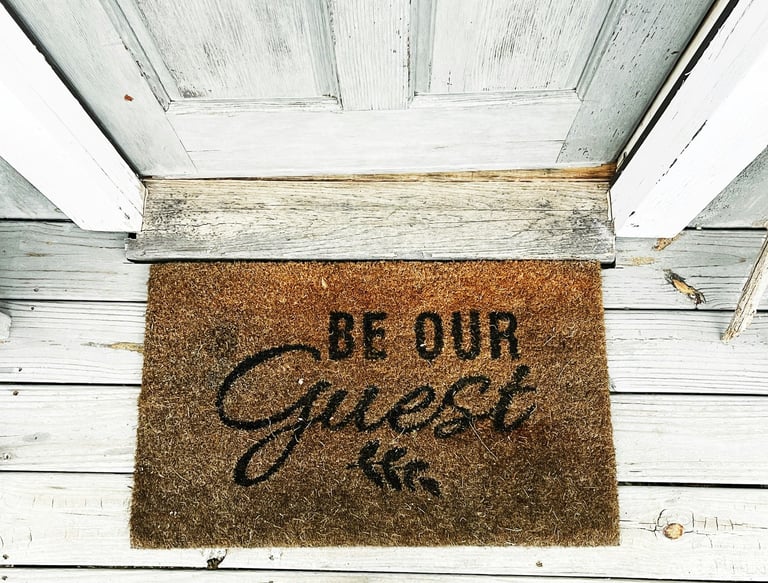 The entrance to the guesthouse with a doormat and the inscription "Be our guest"