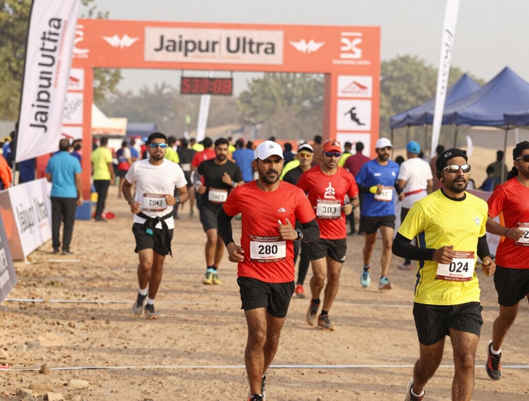 Runners crossing a desert trail with the Jal Mahal glowing in the early morning light.