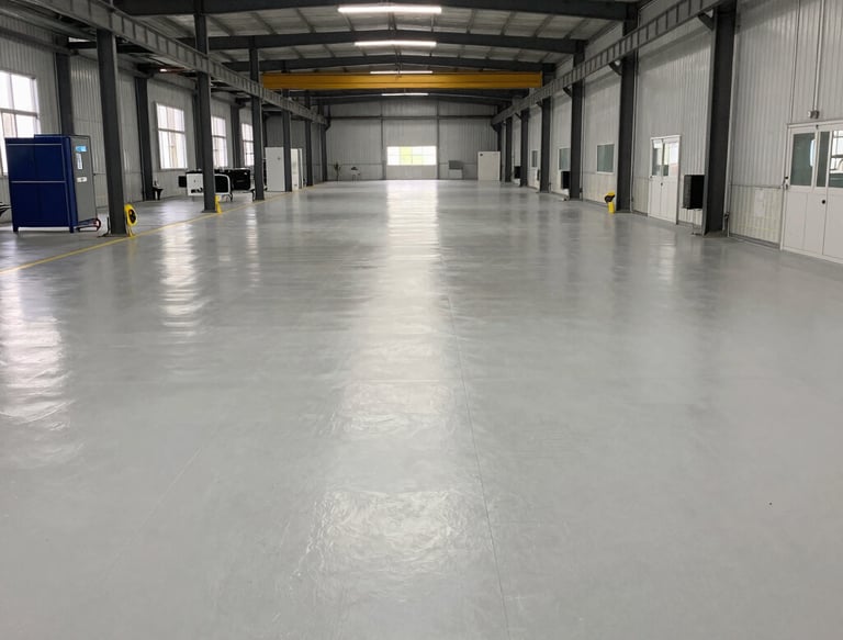 A skilled technician applying epoxy flooring in a modern industrial space.