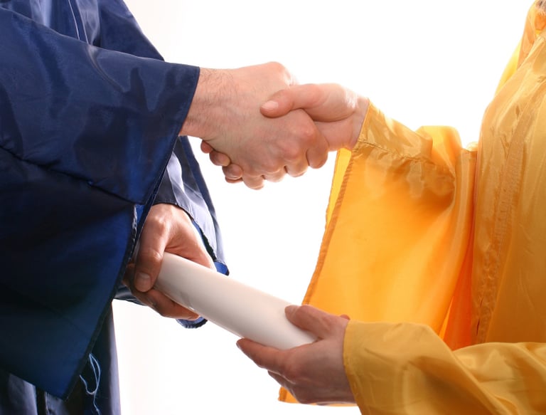 A man and a women shaking hands and holding a diploma