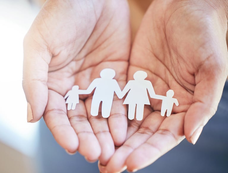 Manos sosteniendo figuras de papel de una familia, simbolizando Derecho de Familia.