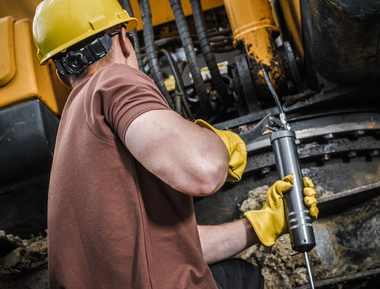 A man greasing his equipment using Grease Dispensers to properly Lubricate his machineries