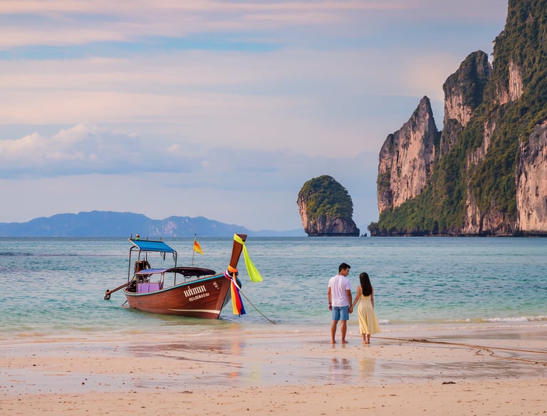 Honeymoon couple enjoying a romantic beach in Phuket, Thailand with limestone cliffs and long-tail boat